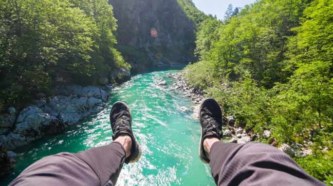 视角：一个人坐在吊桥上，看着山涧咆哮，双脚悬空