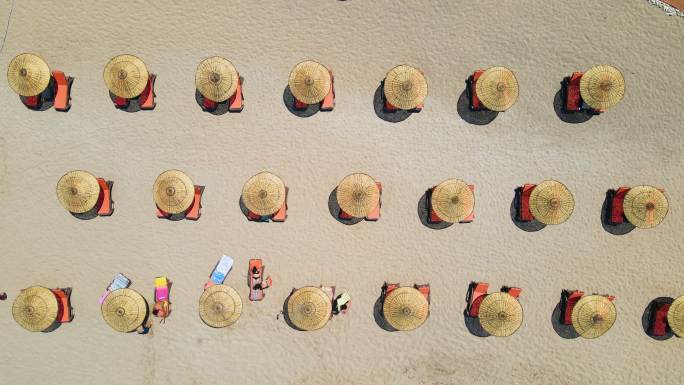 4K分辨率的空海滩上的空沙滩伞，躺椅和海景的鸟瞰图，日光躺椅伞，日光躺椅和沙滩上的雨伞