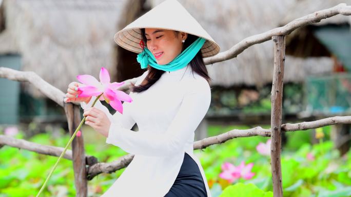 越南妇女坐在莲花田上举着莲花