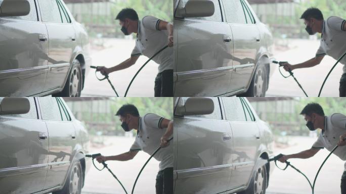 一名亚裔男子在家里用水泵的压力喷雾器洗车
