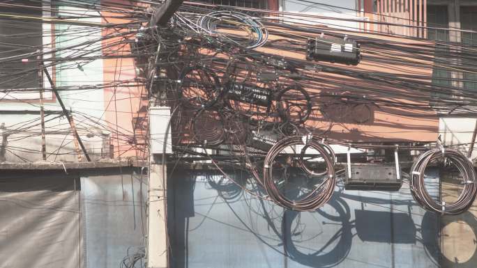在泰国曼谷的街道上，凌乱而纠结的黑色电线，包括电线和电话通讯电缆。