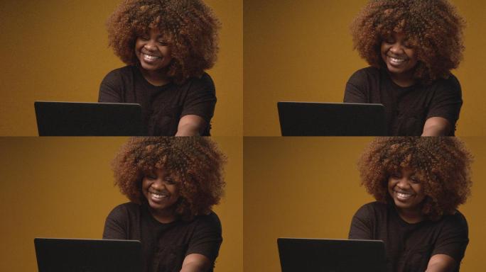 慢镜头工作室拍摄了一位年轻、自信、美丽、专业、快乐的非裔美国女性在笔记本电脑上打字，担任前台接线员、
