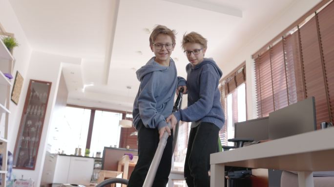 两个小男孩在家用吸尘器清理地毯