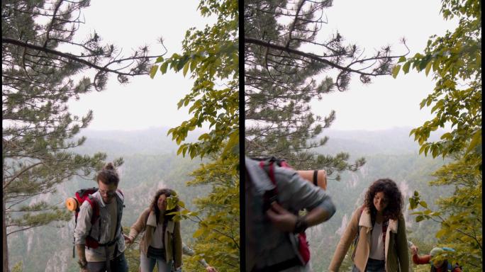 快乐的徒步者在爬山时合作的垂直视频。