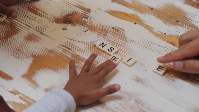一个年轻的家庭在玩拼字游戏，用棋子组成“激励”这个词