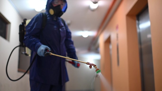 一名身穿防护服的妇女喷洒并消毒走廊灭虫器虫害控制病毒