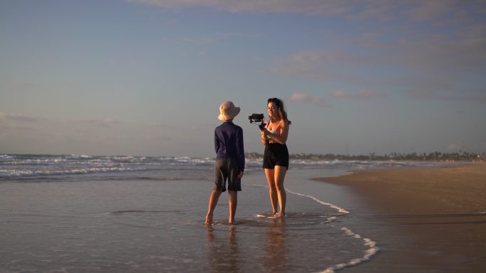 母亲在日出时在海滩上拍摄儿子