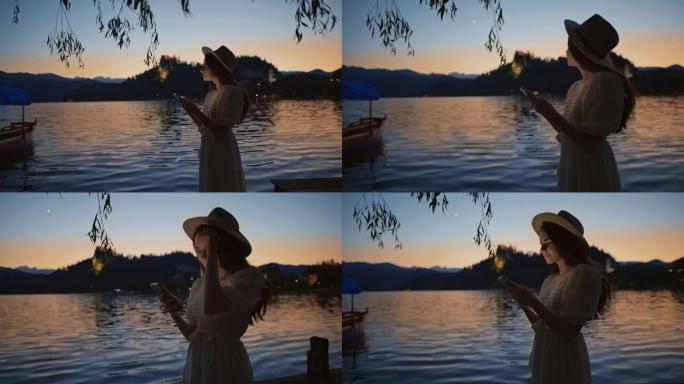年轻女子在黄昏时分在湖边使用智能手机