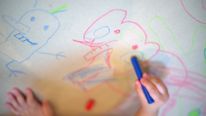 幼儿园孩子在白纸上画动物脸的俯视图。