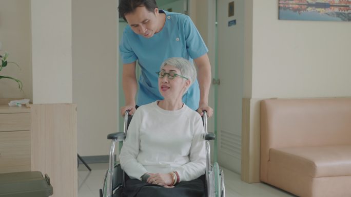 男护理助理坐轮椅关切地与患者交谈。在医院或诊所