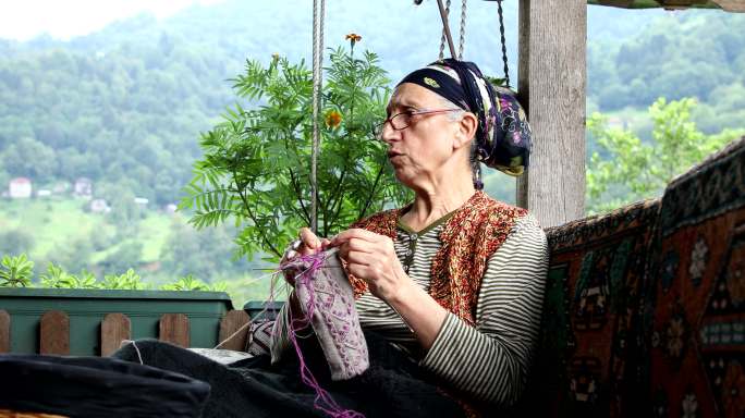 高级成熟乡村妇女在沙发上编织