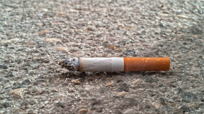 在沥青地面上燃烧的香烟
