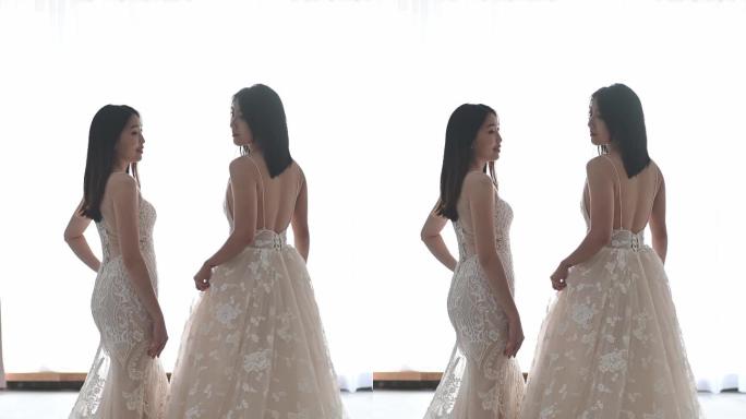 后视图：穿着婚纱的亚裔中国美女在婚纱店摆姿势，在婚纱店微笑