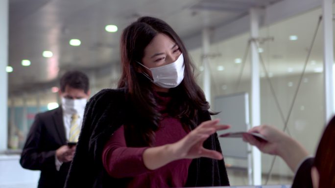 机场值机柜台戴口罩的年轻女子