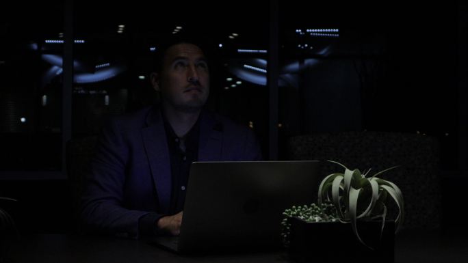 在停电期间，一名成年商人和一名办公室工作人员正在用笔记本电脑拍摄暴风雨夜的4K视频系列