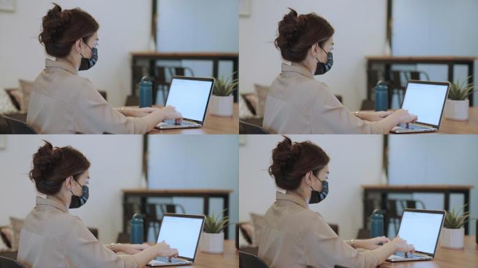 戴口罩在笔记本电脑上工作的亚洲女商人