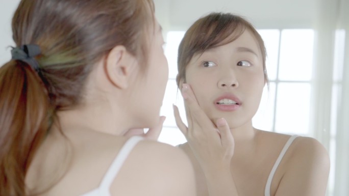 美丽的年轻亚洲女性乐于在面部皮肤上涂抹含有保湿剂的面霜或乳液，美丽的亚洲女孩使用护肤触感面部化妆品，