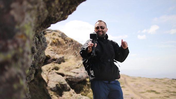 这位徒步旅行者走上山，用他的gopro相机拍摄，为他的viode博客制作视频。