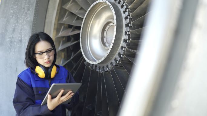 女飞机工程师在机场使用数字平板电脑检查喷气式发动机