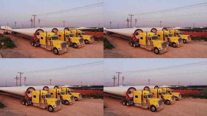 风力涡轮机由超长平板半拖车卡车从墨西哥运过边境，并排停放
