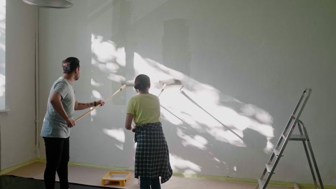 日本夫妇在家用油漆辊粉刷墙壁