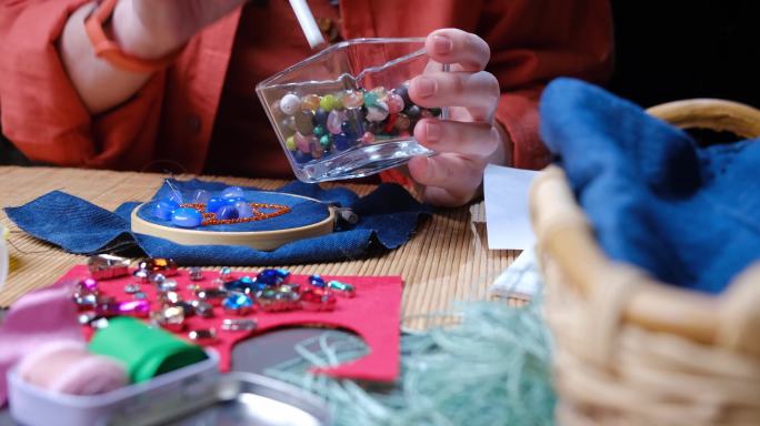 坐在书桌旁，在家里制作珠子和水晶首饰的成熟女人的手