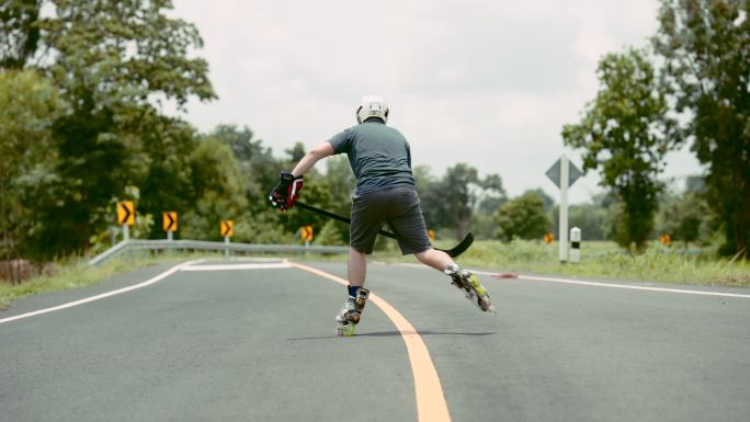 他在户外公路上玩冰球滚轴溜冰。