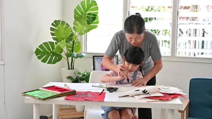 快乐的亚洲小女孩和祖母一起练习中国书法