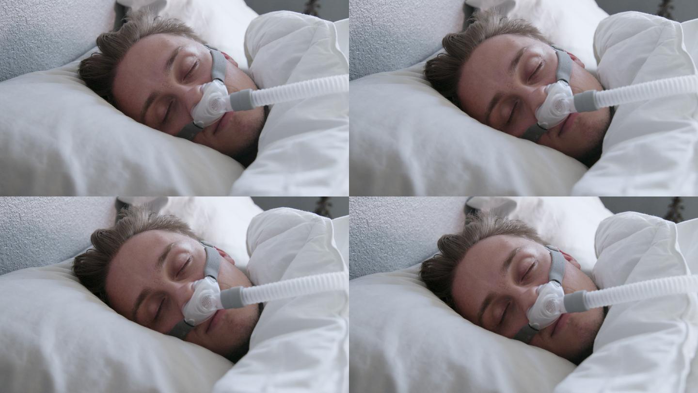 一名患有睡眠呼吸暂停症的年轻男子的特写镜头，他戴着CPAP面罩躺在床上侧卧