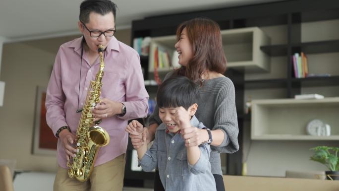 亚裔中国父亲喜欢在周末闲暇时间和家人在家里吹萨克斯管
