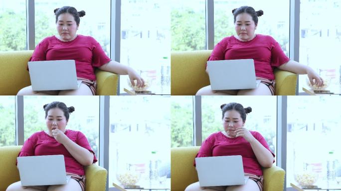 身材高大的女士使用笔记本电脑和平板电脑，亚洲女孩喜欢在家里的沙发上吃东西