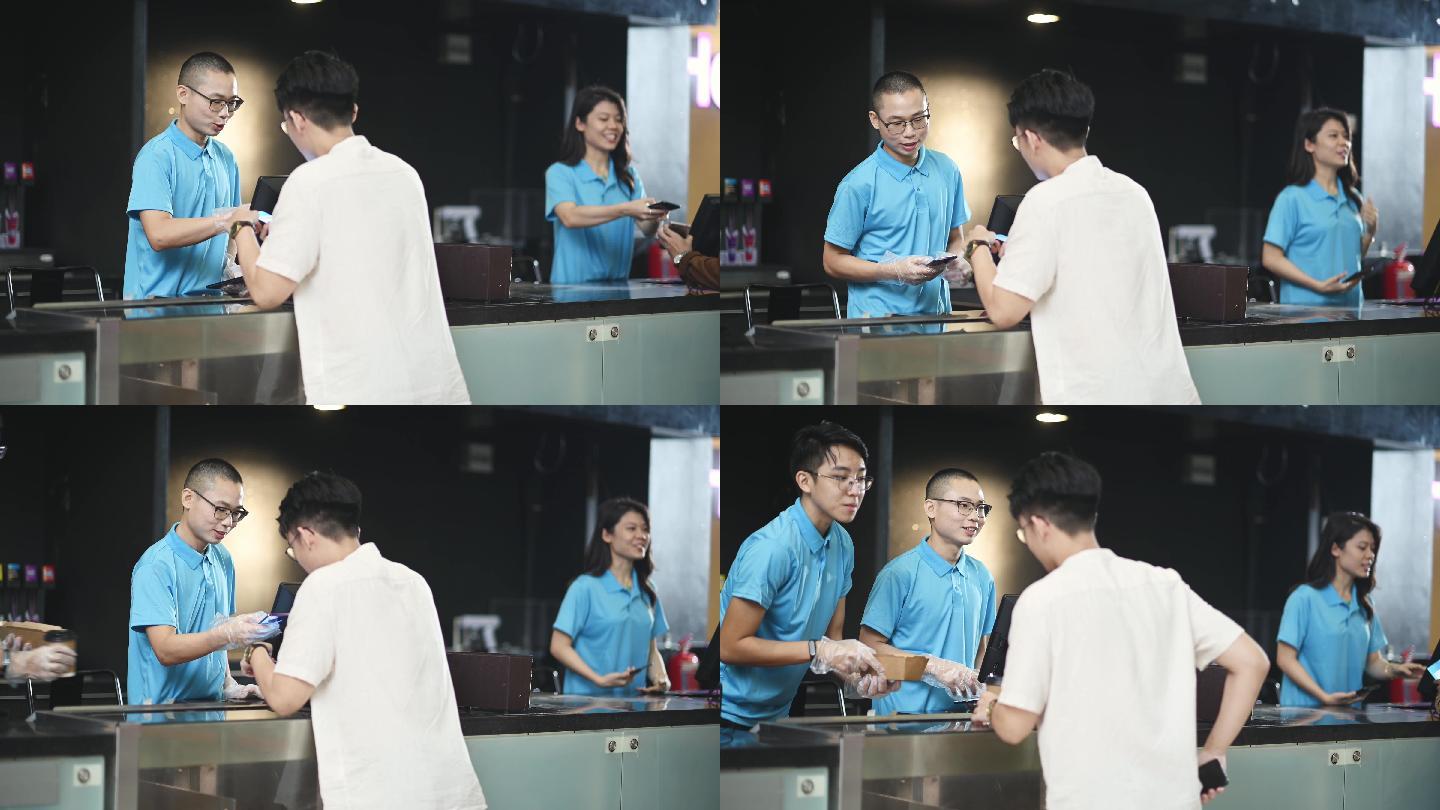 亚裔中国年轻男子在电影院用非接触式支付购买爆米花和饮料