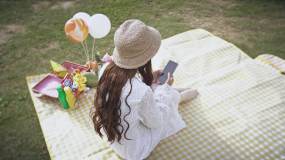 4K唯美小清新少女野餐垫上玩手机实拍视频视频素材