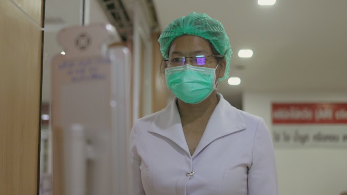 女性医务人员走近一点，站着不动，让摄像头可以聚焦并在智能触摸屏温度计上测量她的体温——库存视频