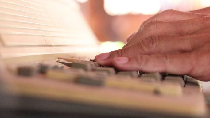 手指在旧打字机键盘上快速按字母的特写镜头。