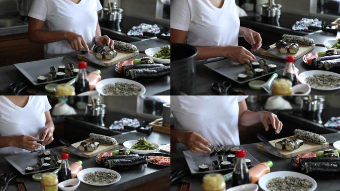 在她的厨房里，一位泰国妇女正在切寿司卷，并把它们放在盘子里
