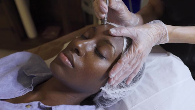 美丽的黑人女子在水疗中心接受面部护理的特写镜头
