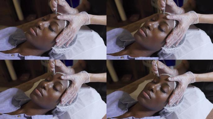美丽的黑人女子在水疗中心接受面部护理的特写镜头
