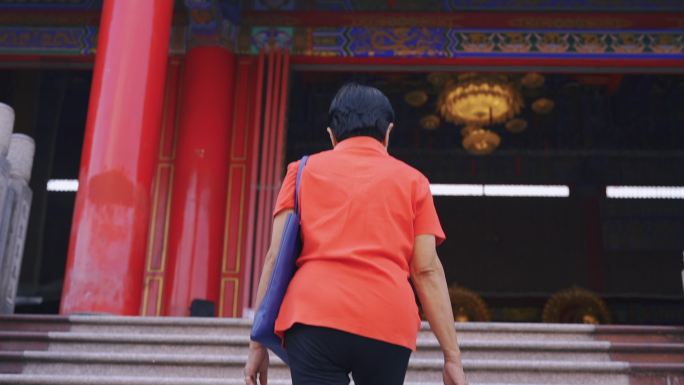 亚洲高级女子在寺庙里祈福。