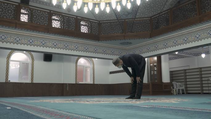 一名戴着口罩的穆斯林男子正在清真寺做礼拜