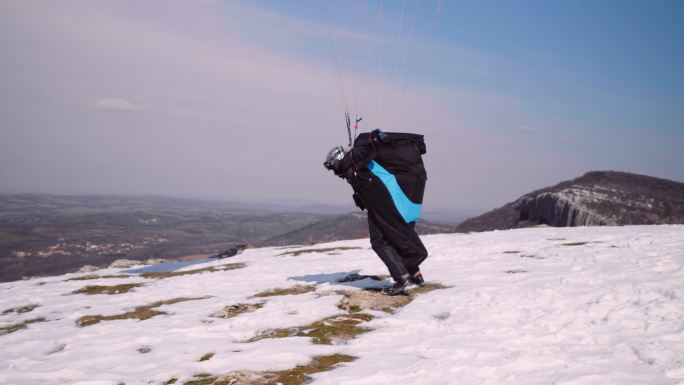 在阳光明媚的冬日滑翔伞，鸟瞰图。极限运动和冒险的越野飞行员。