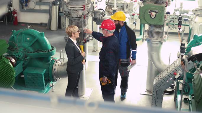 一名身着工作服的妇女与穿着工作服的供暖工人交谈。