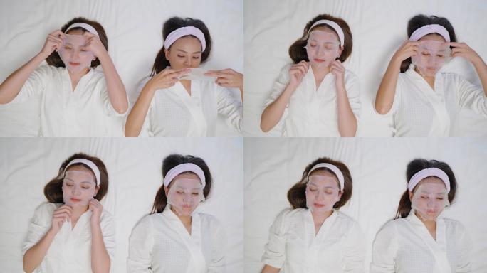 俯视图：一位年轻的亚洲美女和她的朋友戴着面膜，在家里的卧室里进行水疗，情绪积极，面带微笑，心情愉快。