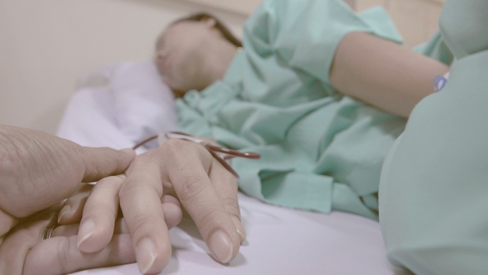 4K：丈夫们在医院病床上牵着妻子的手，怀里抱着静脉输液