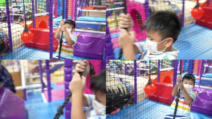 亚洲小孩戴着医用口罩在室内游乐场玩耍。保护、创造力和学习的概念