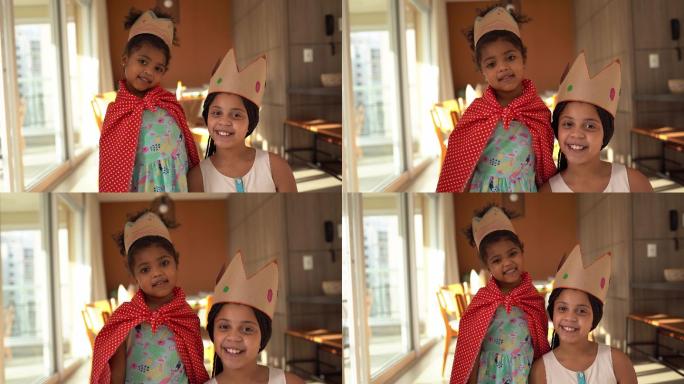 可爱的姐妹们在家里戴着皇冠玩耍的照片