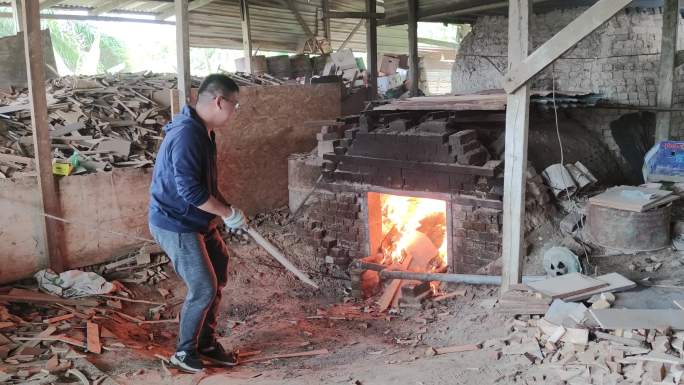亚洲华人成熟男子正在烧窑烘干陶器。
