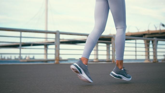 在高桥上的跑道上，从女性跑步者双腿的侧面观看
