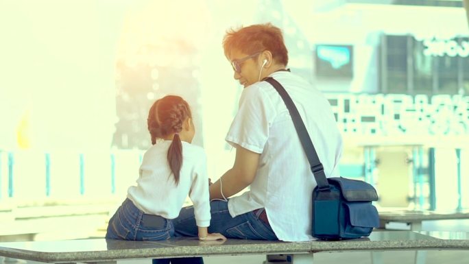 单亲父亲或单亲继父和女儿在火车站触摸屏手机