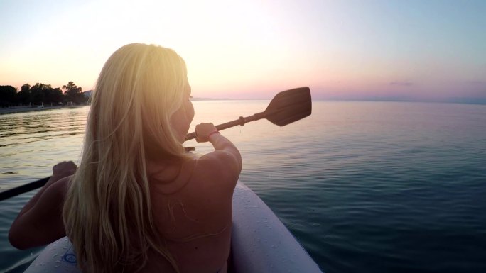日落时在爱琴海划船的年轻女子